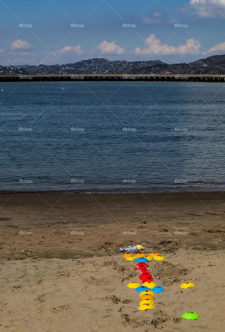 Children’s toys and a doll left abandoned on the beach at Aquatic Park in San Francisco California just waiting for someone to return to play with them 