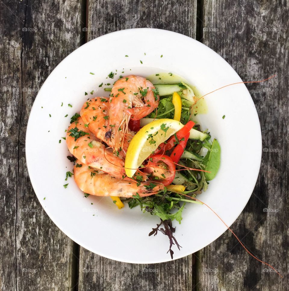 A flat lay food image of a healthy seafood platter with salad and lemon in a square Instagram style frame