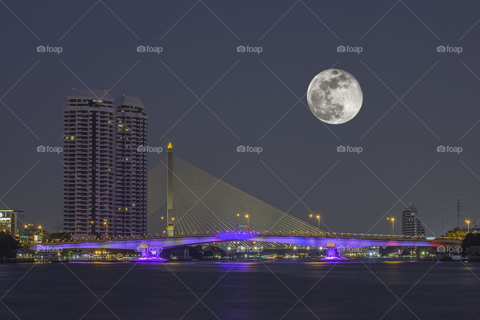 Full moon In the dark sky and The Beauty Of The Chao Phraya River and the lights of the car on Pinklao bridge at Night  , Bangkok in Thailand.