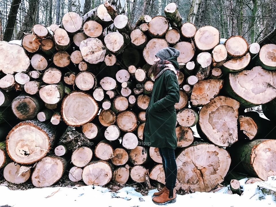 Woman standing near stack of wooden logs