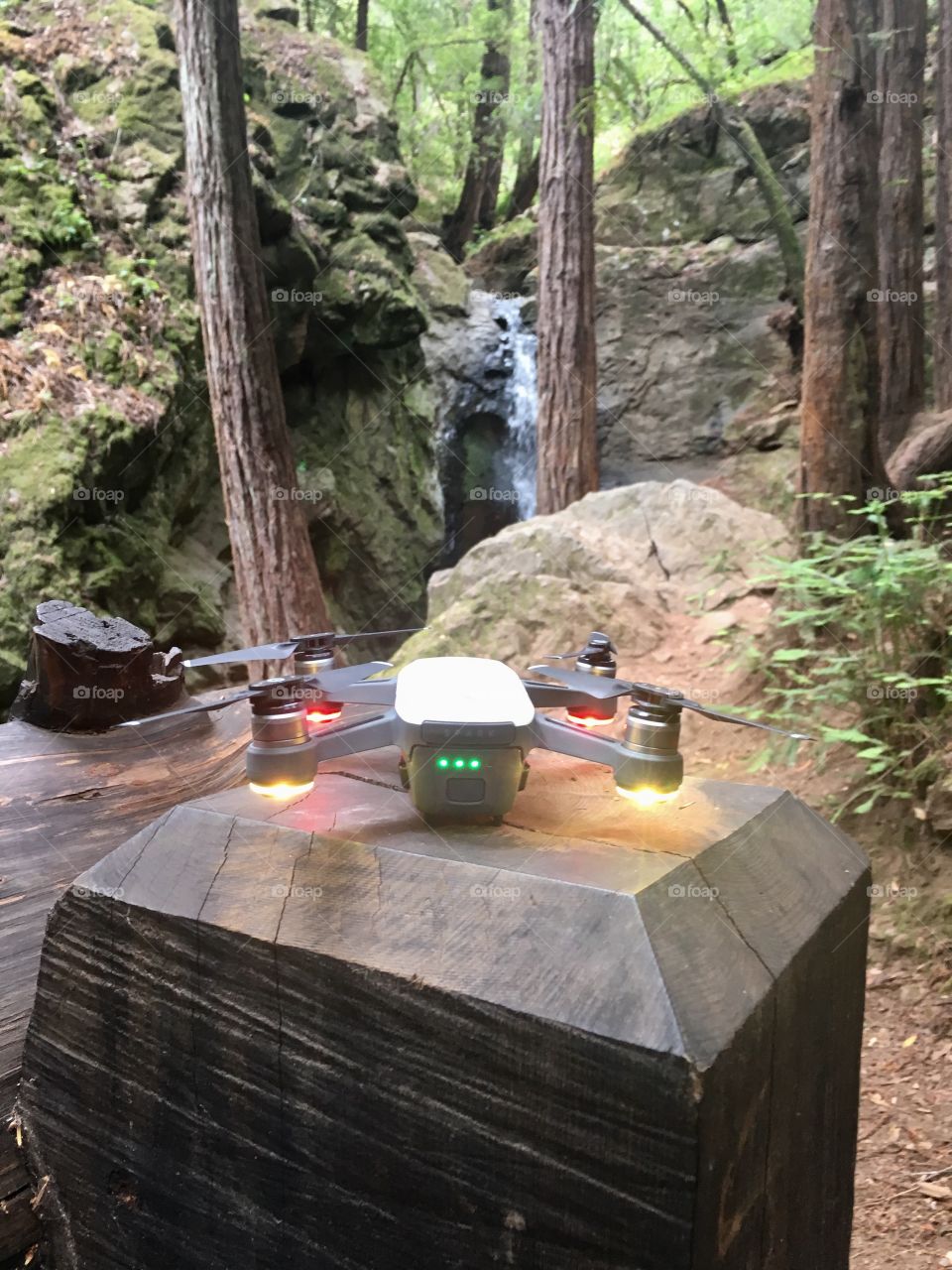 DJI Spark drone ready for take off in a forest with a beautiful waterfall in the background 