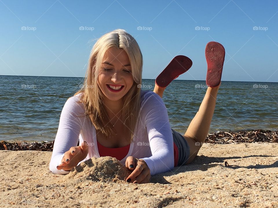 Happy woman playing with sand at beach