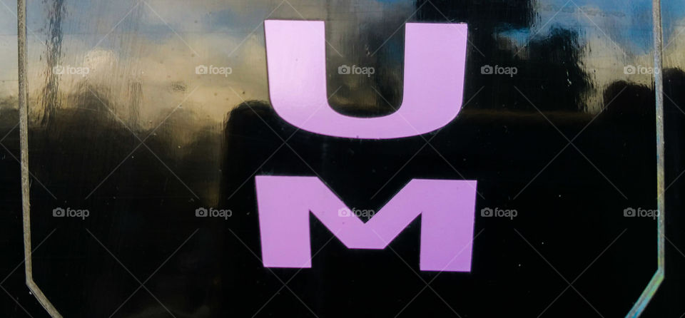 Purple letters UM on a shop window with some reflections