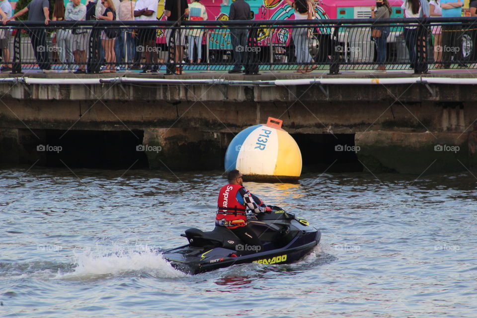 Man with bright red life vest sitting on jet-ski on Hudson River 
