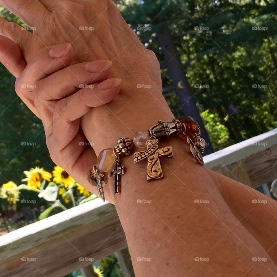 This photo is in a shaded area. It's a charm bracelet with hearts, different style crosses & colored beads on a string with clasp closure.