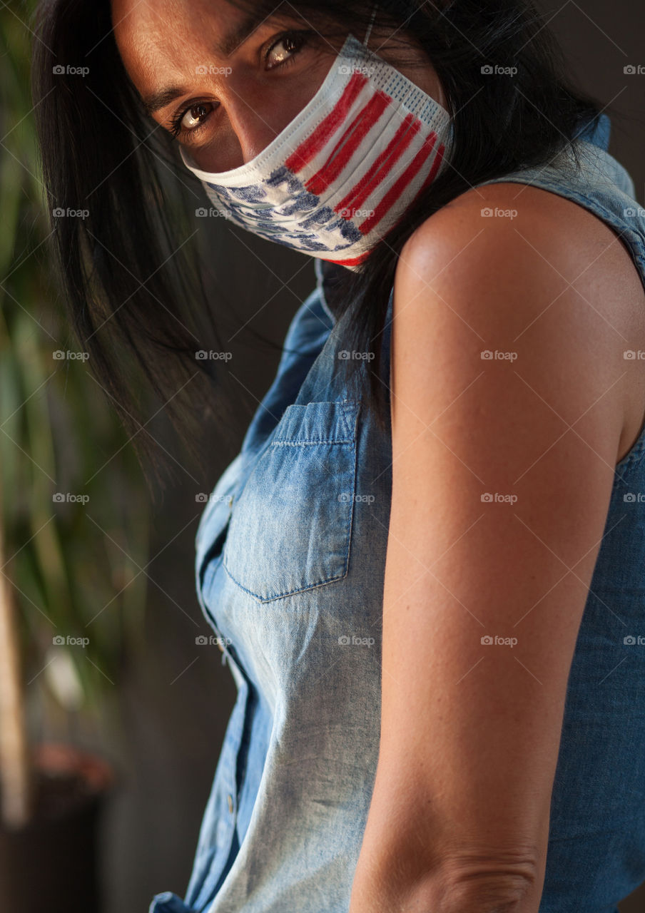 Beautiful brunette in a protective mask painted by the American flag. Independence Day in America. Flag. Love. A life. The mask is made by hand