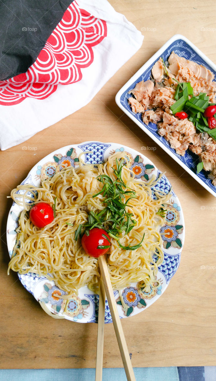 Noodles on a pretty oriental plate, chopsticks, tomatoes, herbs