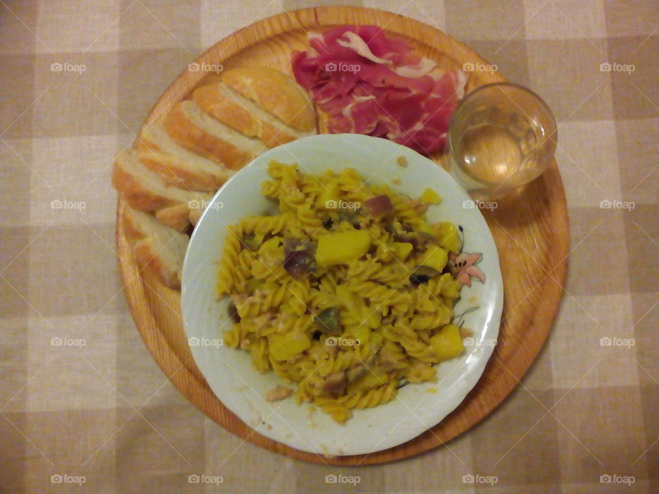 In the kitchen. Pasta prosciutto bread and water on wood