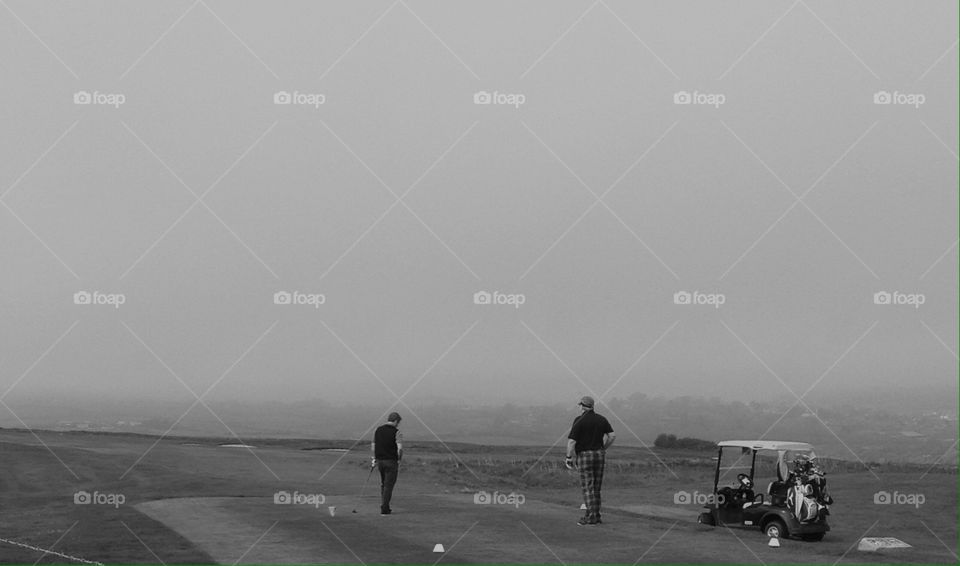 golf players, foggy day.  dorset, united kingdom 