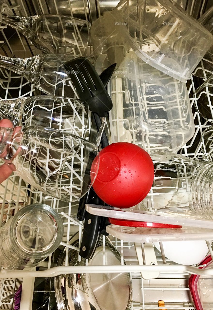 Single red dish on top rack of automatic dishwasher 