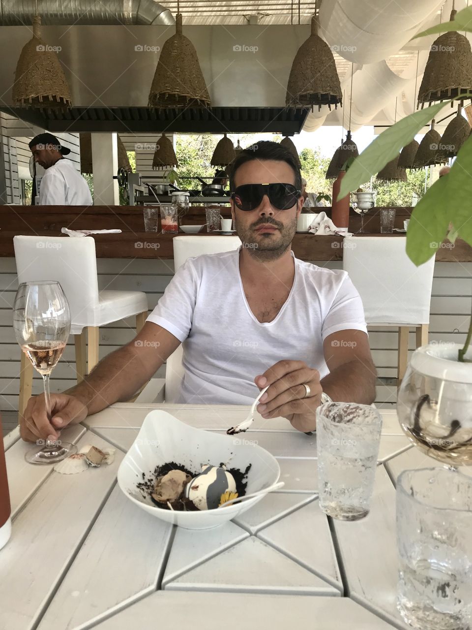 Guy eating dessert and drinking wine at a beach bar type setting