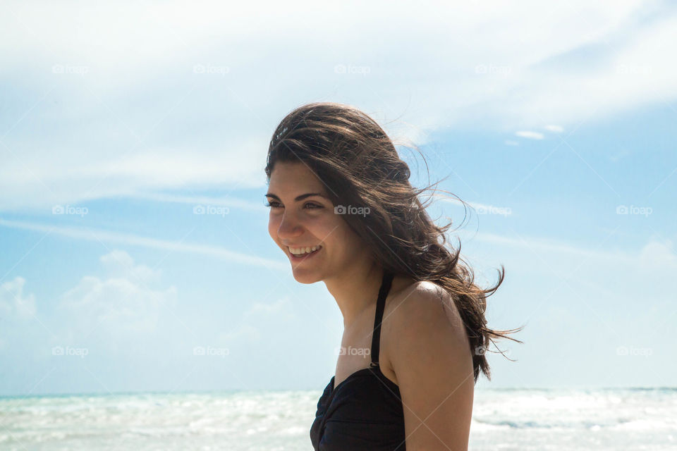 Happy girl on beach, brunette hair wavy