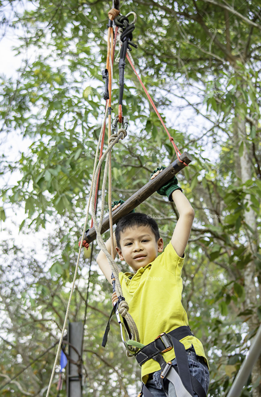 Asean boy hanging rod Tied with ropes and slings background blurry tree.
