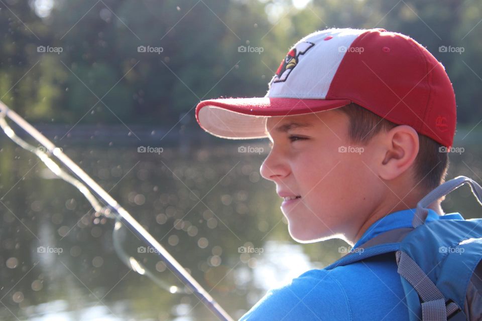 Boy fusing in pond at golden hour