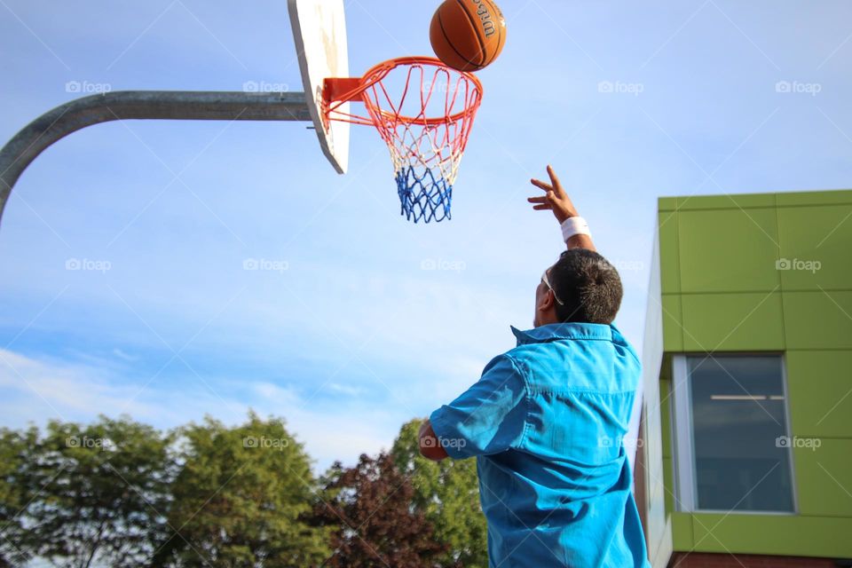 Man is throwing a basketball into the hoop