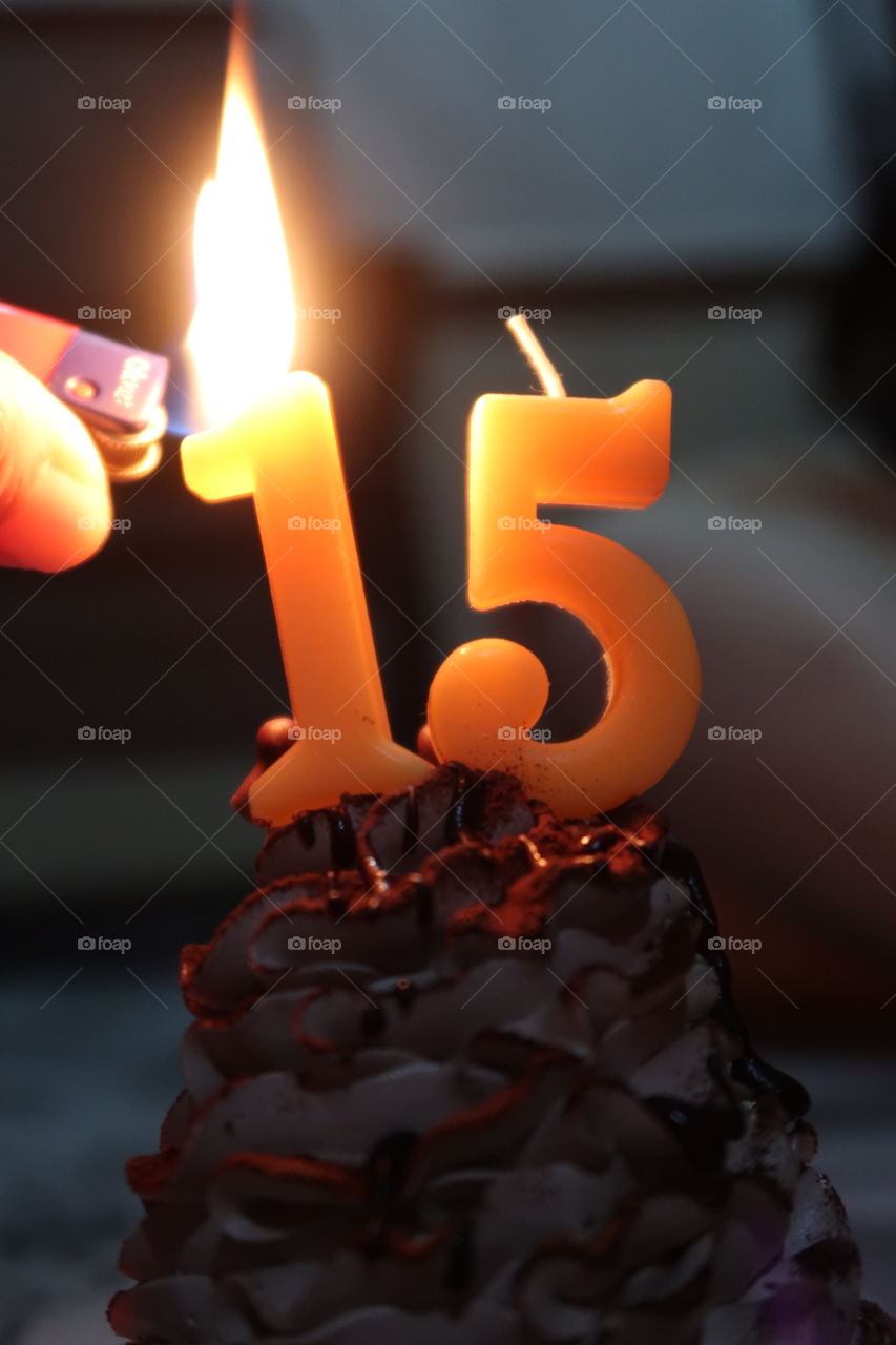 A person ignites candles on birthday cake