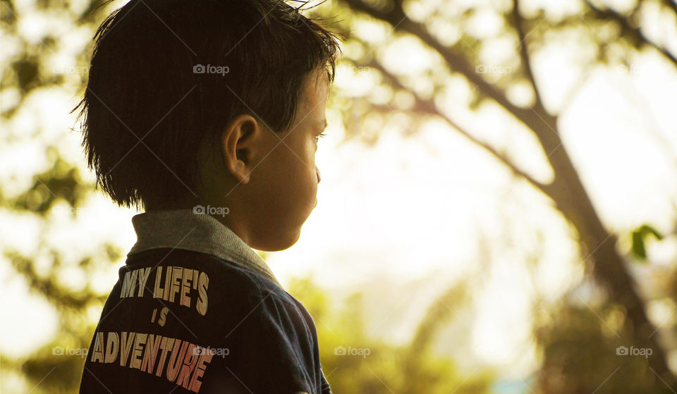 Close-up of a boy standing in front of trees