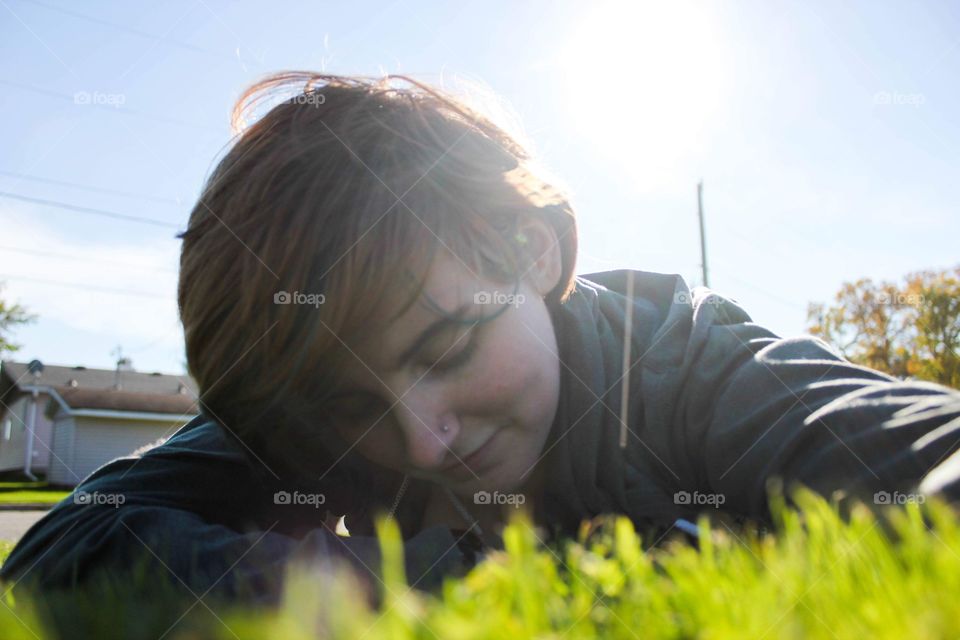 Portrait of a young woman laying in the grass in summer