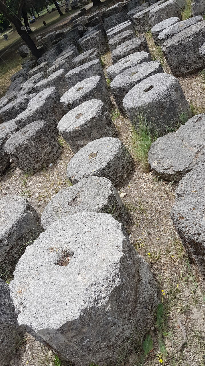 Fallen marble pillars of ancient Greece in Olympia, ruins of historical site on sunny summer day