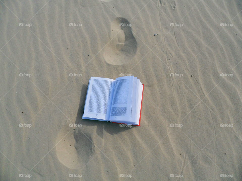 An open book lies on the sand