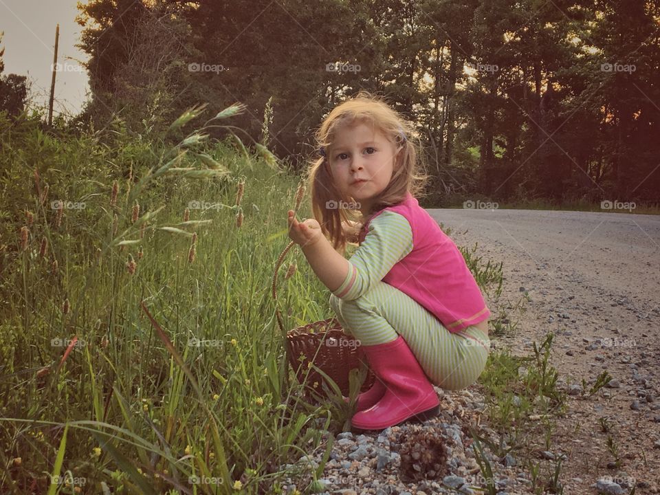 Girl crouching near grass with basket in hand