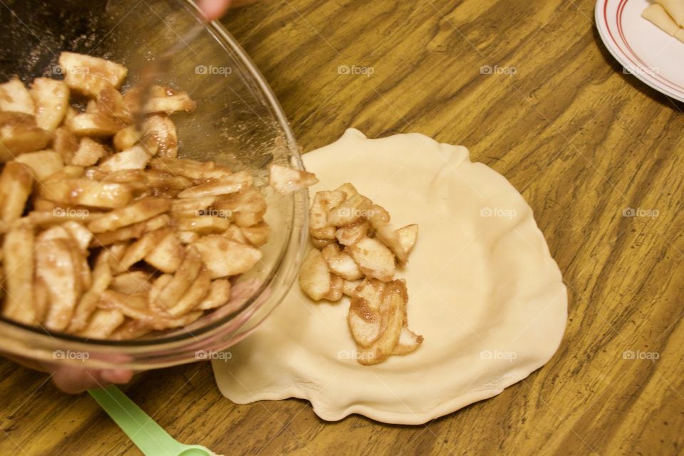 Pouring apple slices into a pie shell 