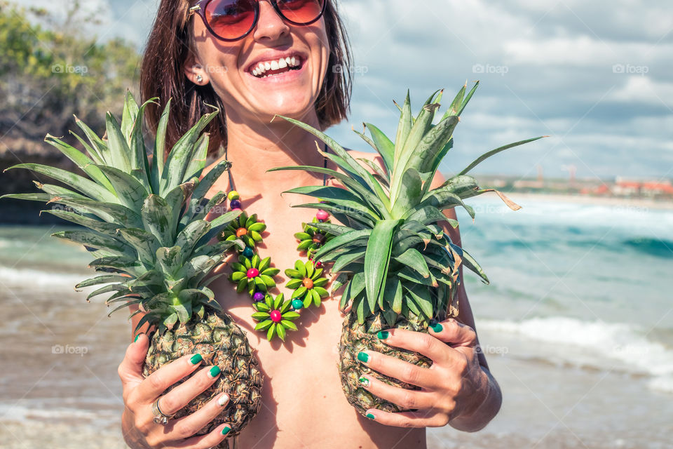 The girl is photographed on the beach with pineapples. Bali island.