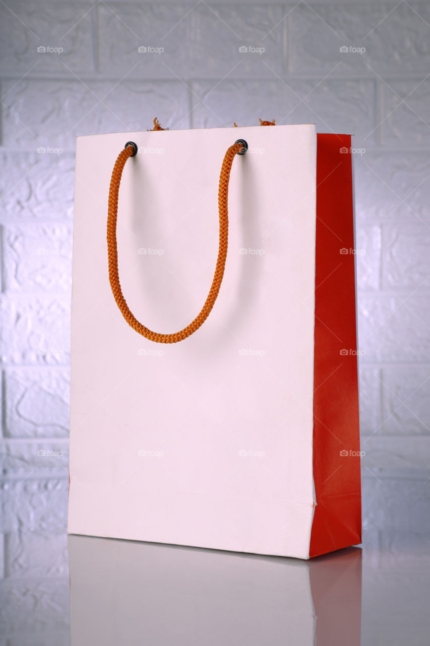 White and orange shopping bag mockup on a brick wall backdrop
