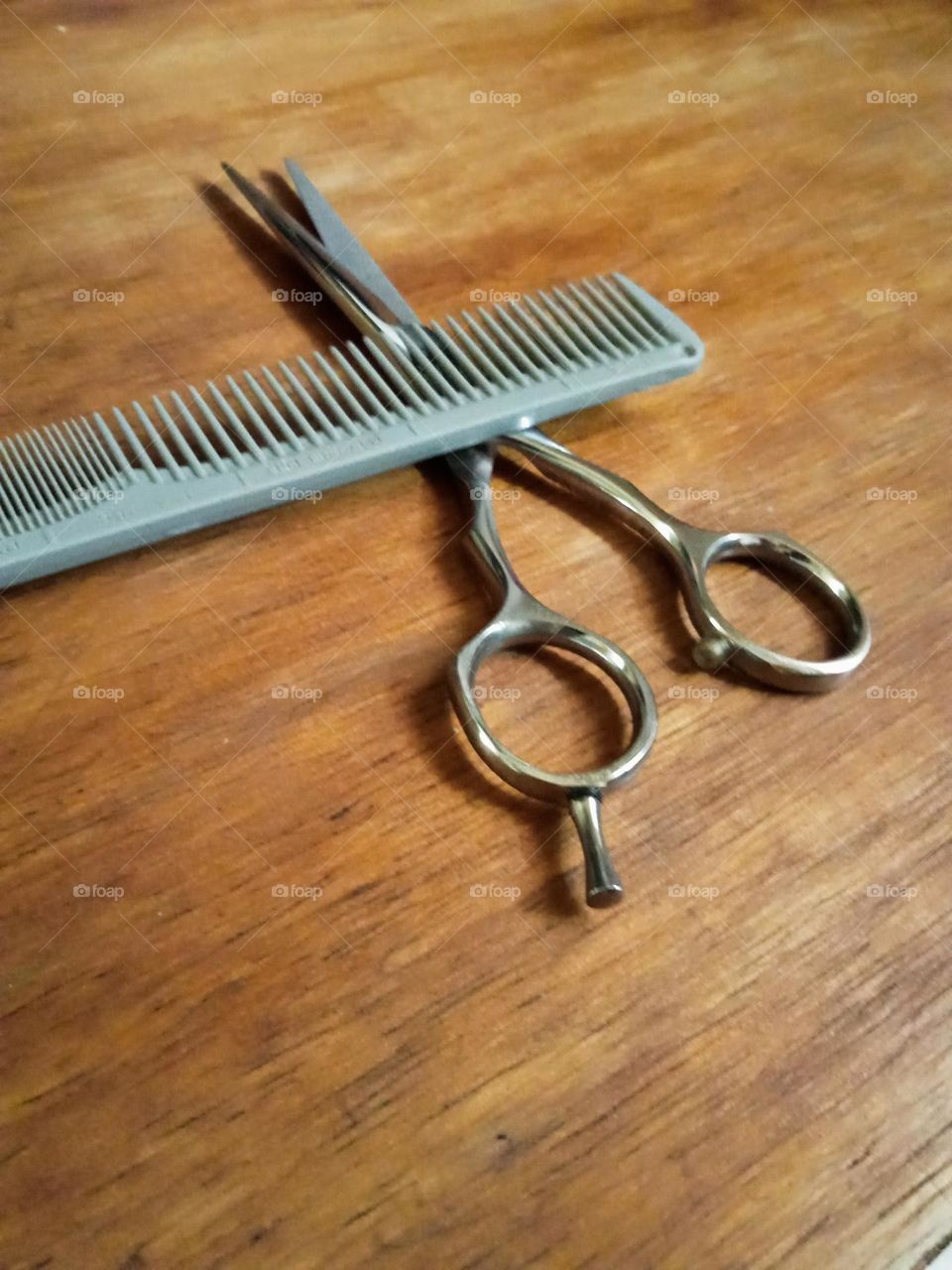 A pair air cutting tools, comb and scissor on the table.