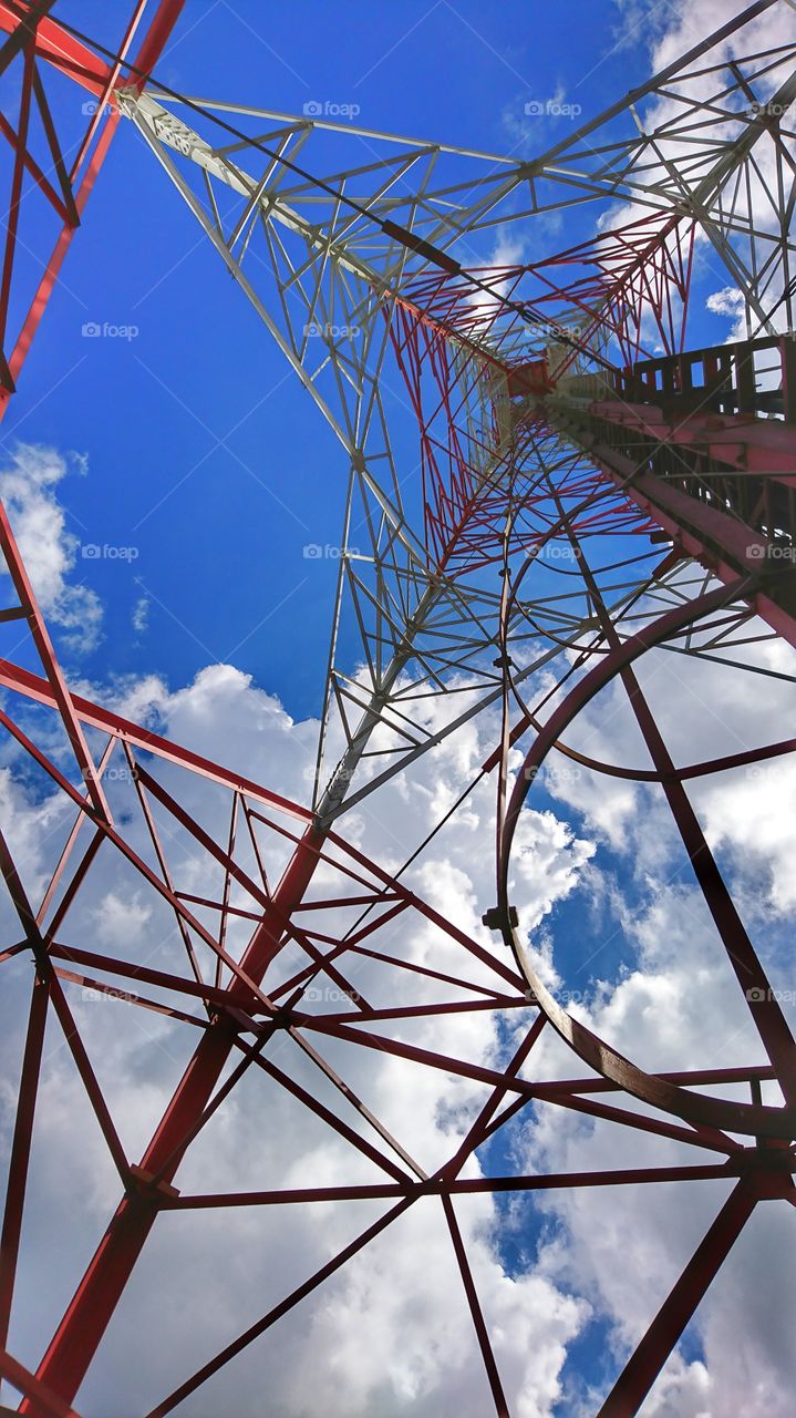 Structure of mobile phone tower from below to top on cloudy and blue sky background