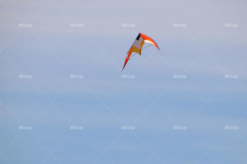 Close-up of an orange stunt kite in the blue sky