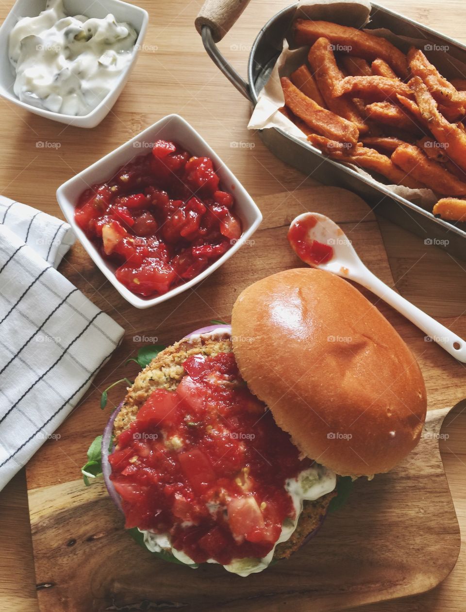 Spicy bean burger with tomato relish and sour cream served with sweet potato fries 