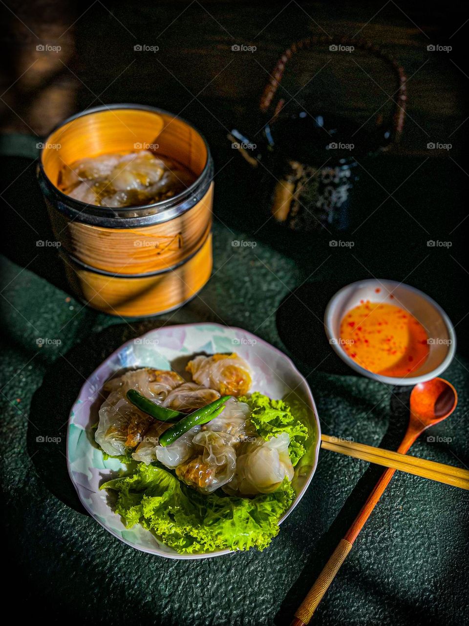 Crystal shrimp dumplings with spicy sauce on a dark table