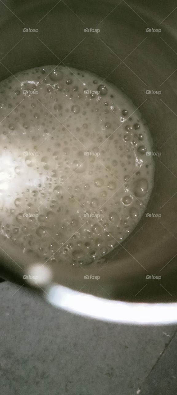 Bubbles on just removed fresh sugarcane juice. This juice is in circle shape bottle. It's nice to drink fresh, cold and sweet sugarcane juice for well health.