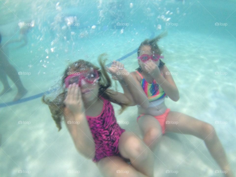 Underwater tea party. Underwater view of girls sitting on the bottom of the pool 