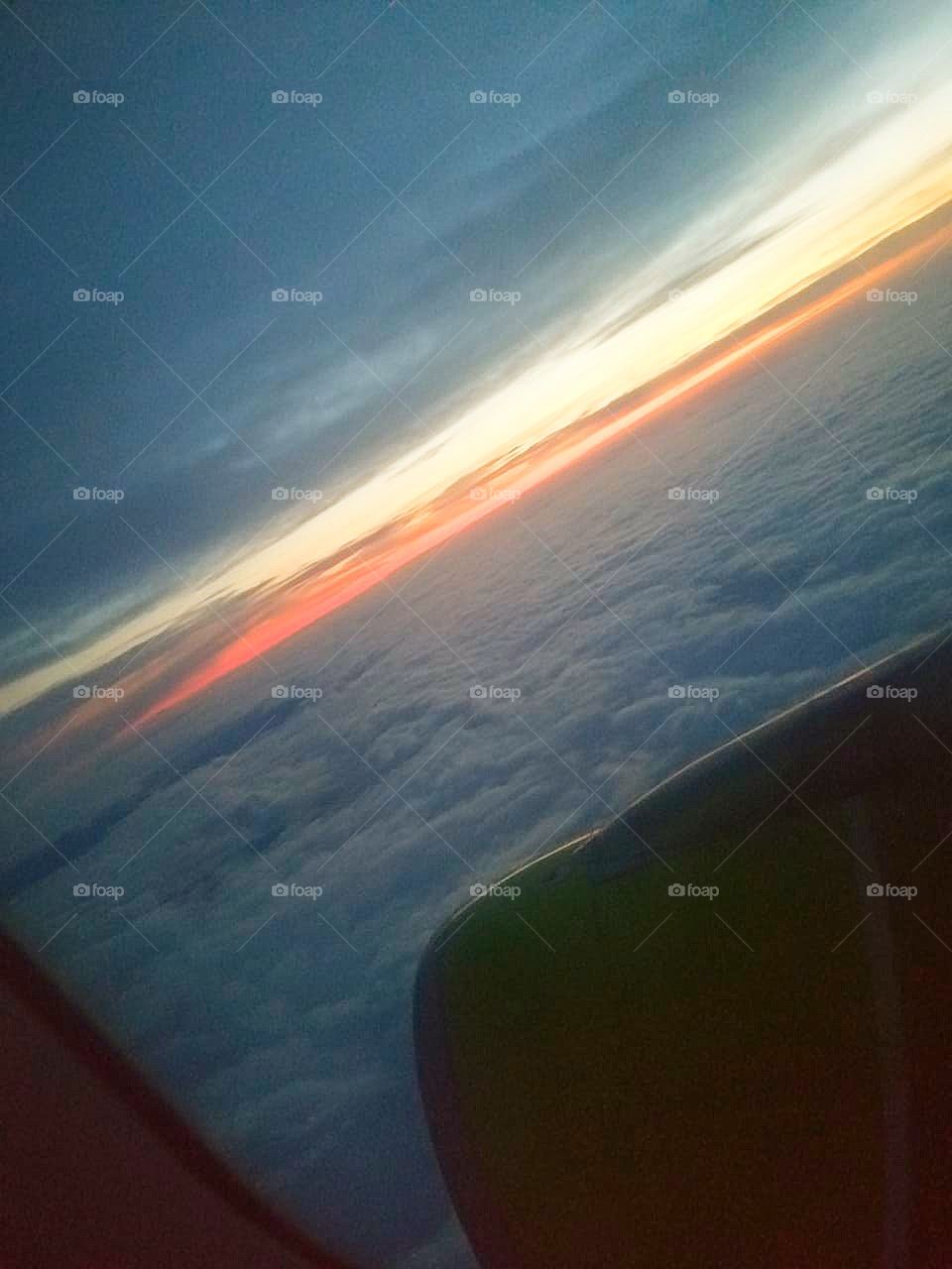 The plane is gaining altitude.  A carpet of clouds over the plane.  Sunset