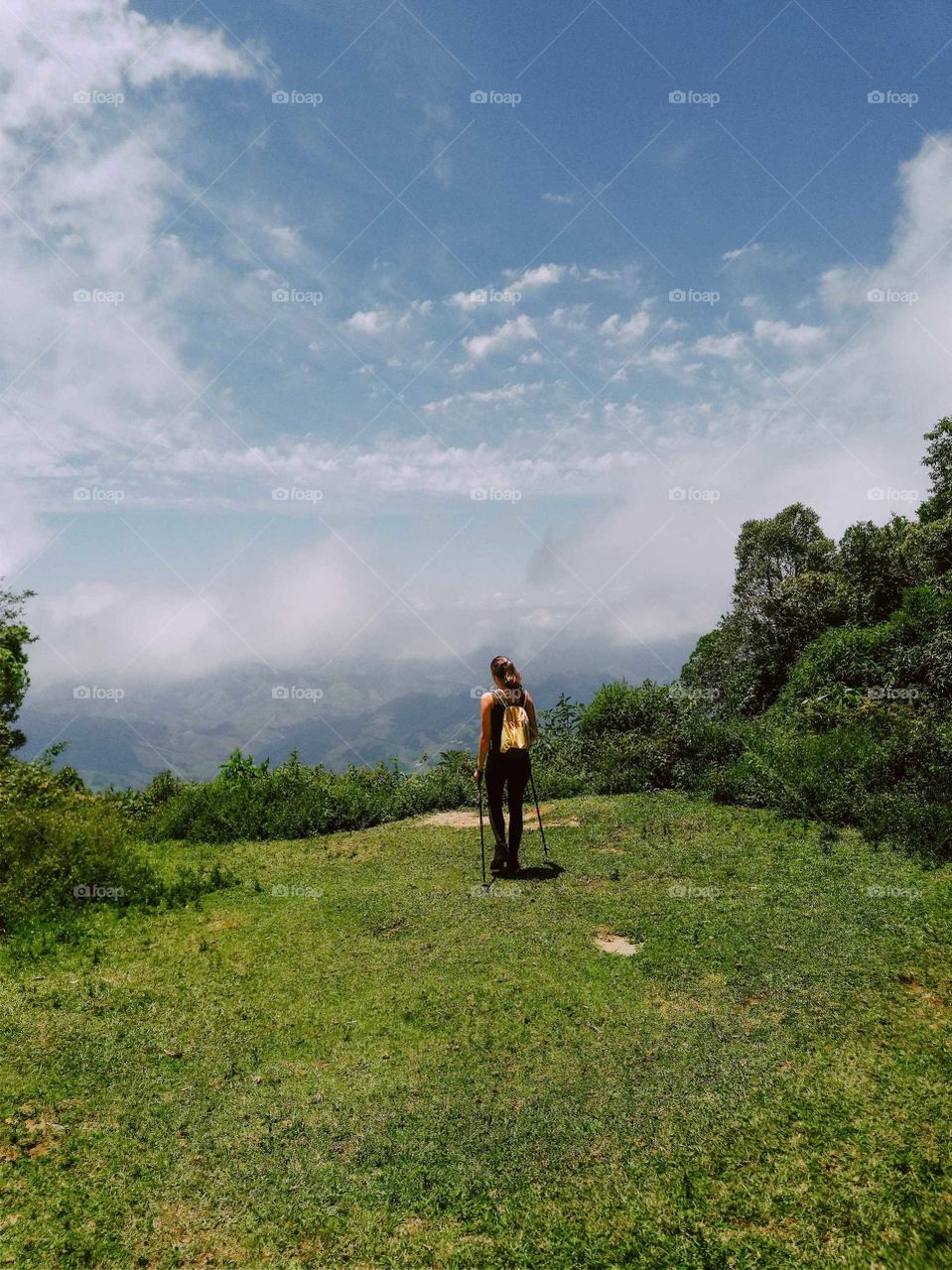 Beautiful Blonde Girl at the São Francisco Xavier Mountains, Brazil. Beautiful green grass and blue sky, with climbing equipment.