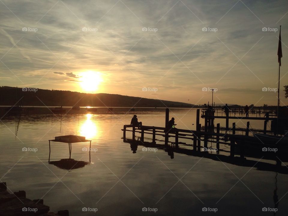 Two people sitting on pier