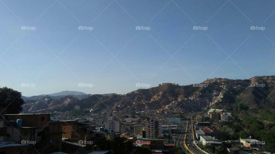 Hermosa vista desde la ventana de mí casa, un cielo azul intenso al fondo una gran montaña con cualquier cantidad de casas, son los hogares de la gente humilde en Venezuela.