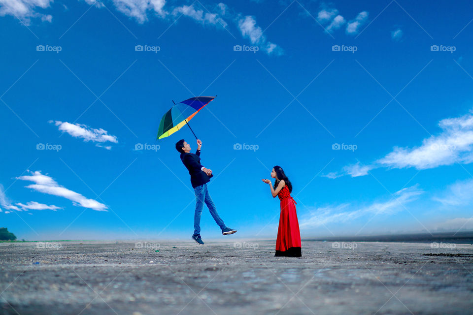 Woman flying in air in front of woman at beach