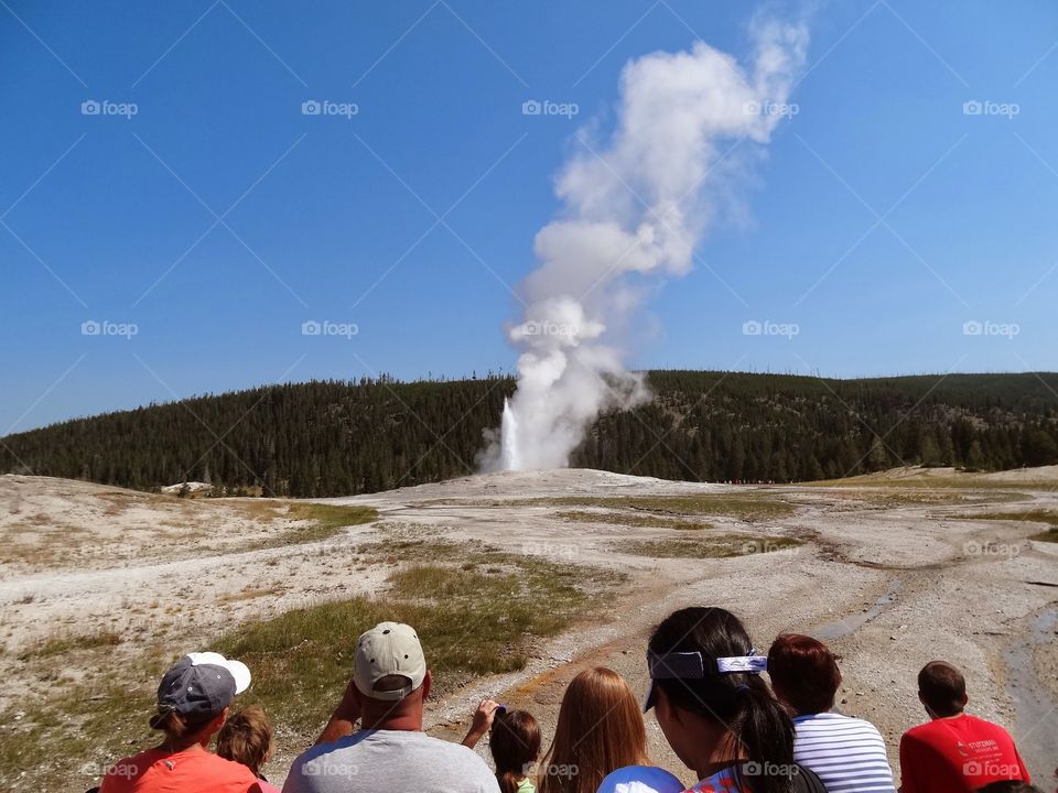 Old Faithful Getting Started. Group watching Old Faithful just beginning an eruption.