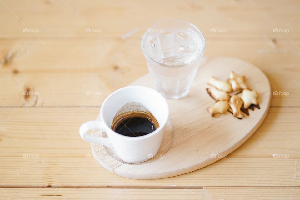 Espresso. A cup of espresso with iced water served on wooden table.