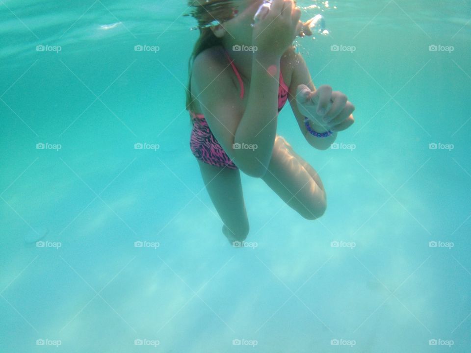 View from down under. Underwater view of a girl swimming