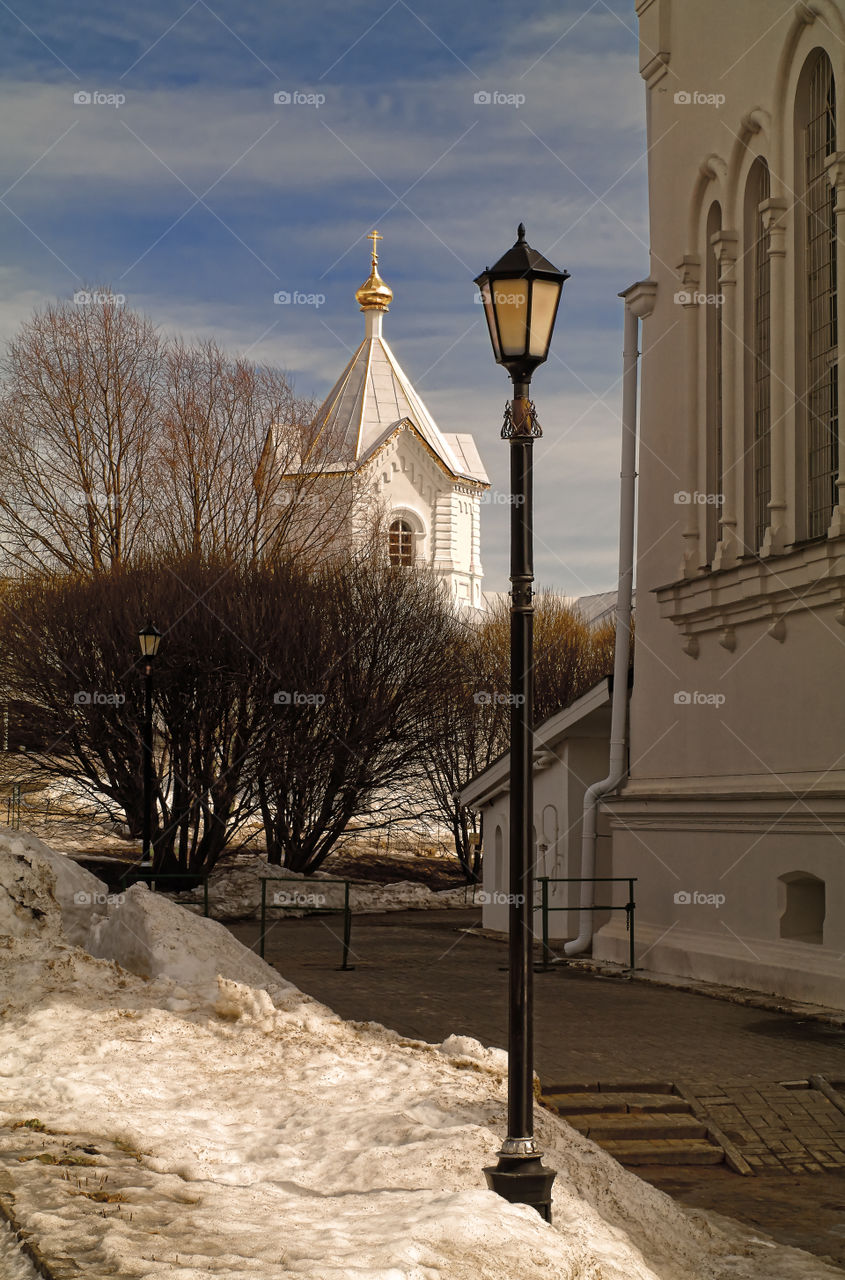 View of the lantern and the chapel in the Holy Trinity Seraphim-Diveevsky monastery (Russia, Diveevo) and the snowballs began to melt snow in early spring against a cloudy sky on a sunny spring day