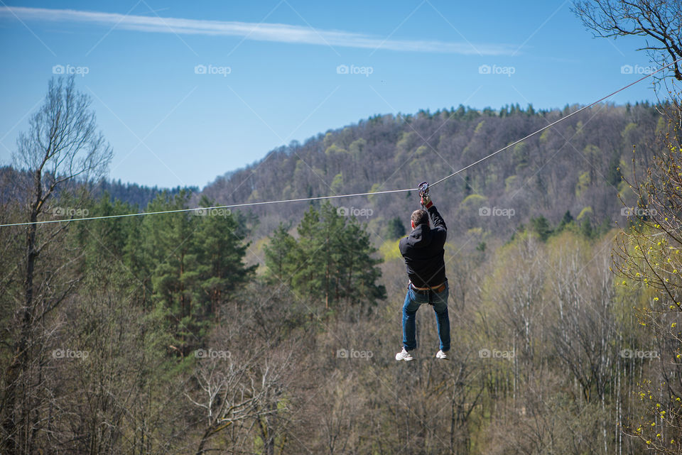 Zipline is an exciting adventure activity. Man hanging on a rope-way.