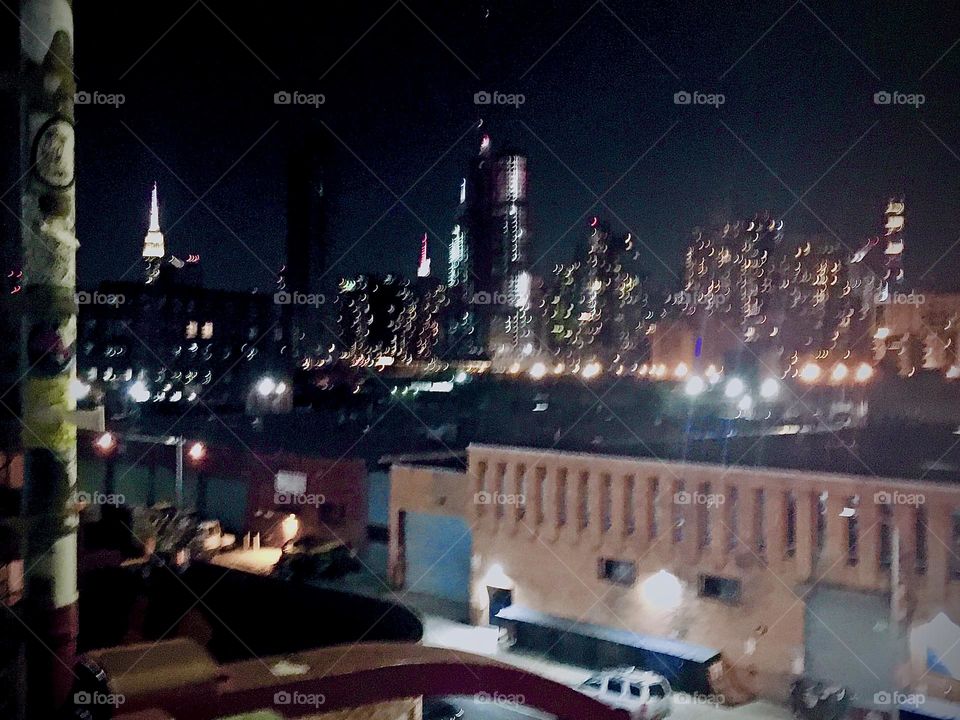 This nighttime photograph was taken from the “Greenpoint”, Brooklyn side of the “Pulaski Bridge” standing on the staircase looking across the “East River” onto LIC, Queens and “Manhattan” incl. the “Empire State Bldg”. 2022. Hypnotic Productions
