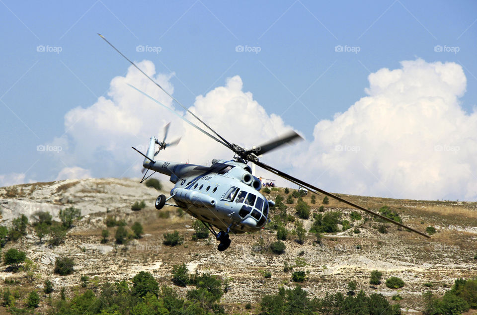 The military helicopter's flying over hill at the morning