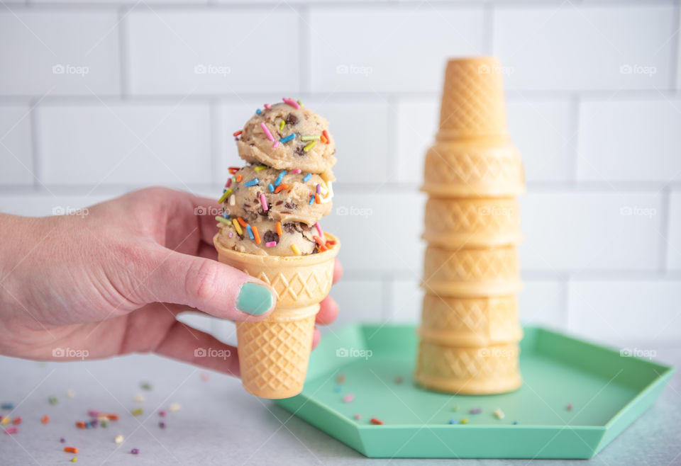 Person holding an ice cream cone with sprinkles 