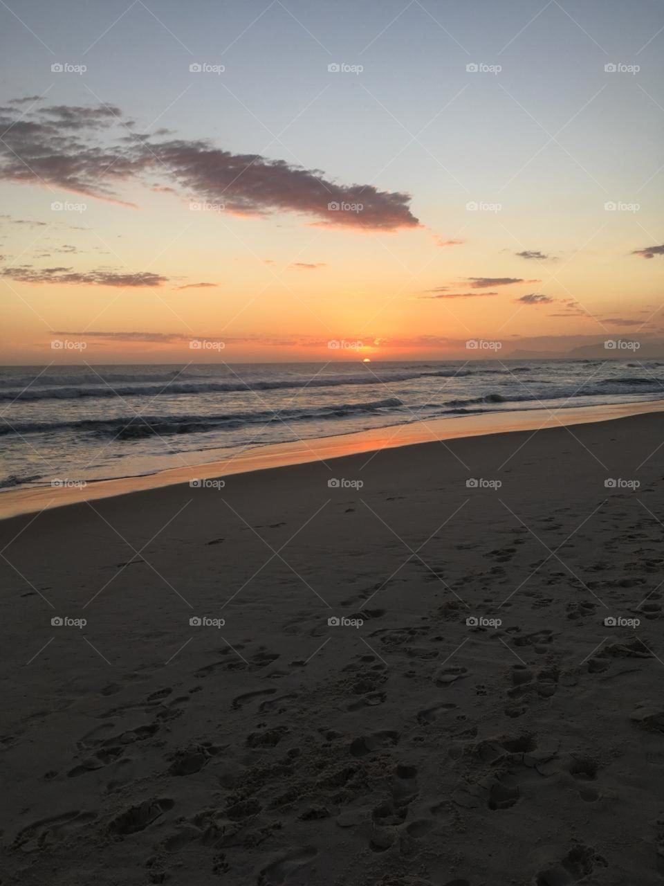 O por do sol no Rio de Janeiro. Veja que céu maravilhoso e as pegadas na areia fofa da praia. 