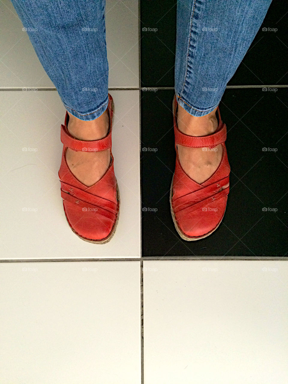 Standing with red shoes on black and white tiles